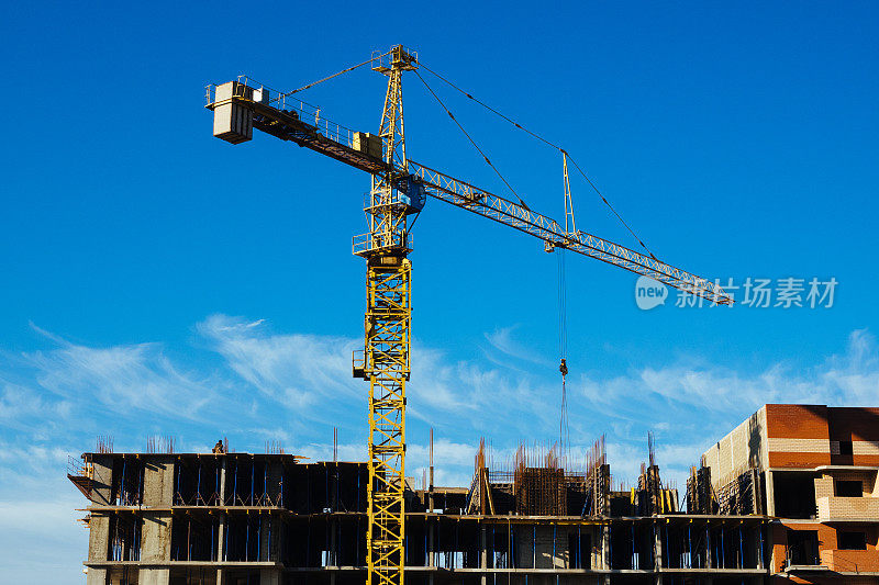Construction crane against the blue sky. Construction of a multi-storey building